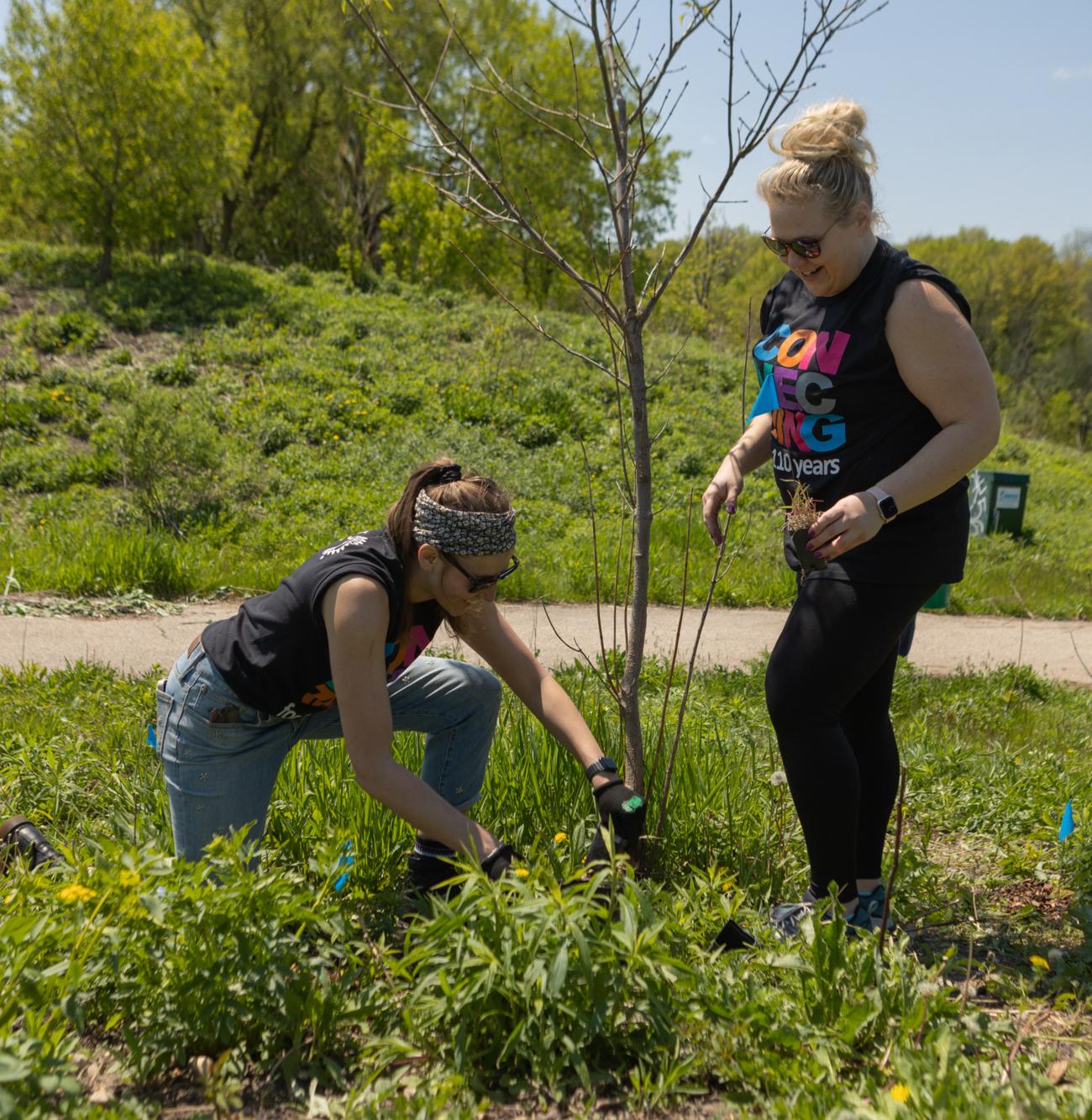 Paige Radke (left), of the Rotaract Club of Milwaukee, and Janine Kolbec, club member. Members of the Rotary Club of Milwaukee, Wisconsin, USA, and other volunteers plant prairie grasses along the Milwaukee River. The club spearheaded an initiative to transform industrial land along the river into an arboretum. Members of the club have been active in habitat restoration efforts since the park opened in 2013. Milwaukee, Wisconsin, USA. 20 May 2023.